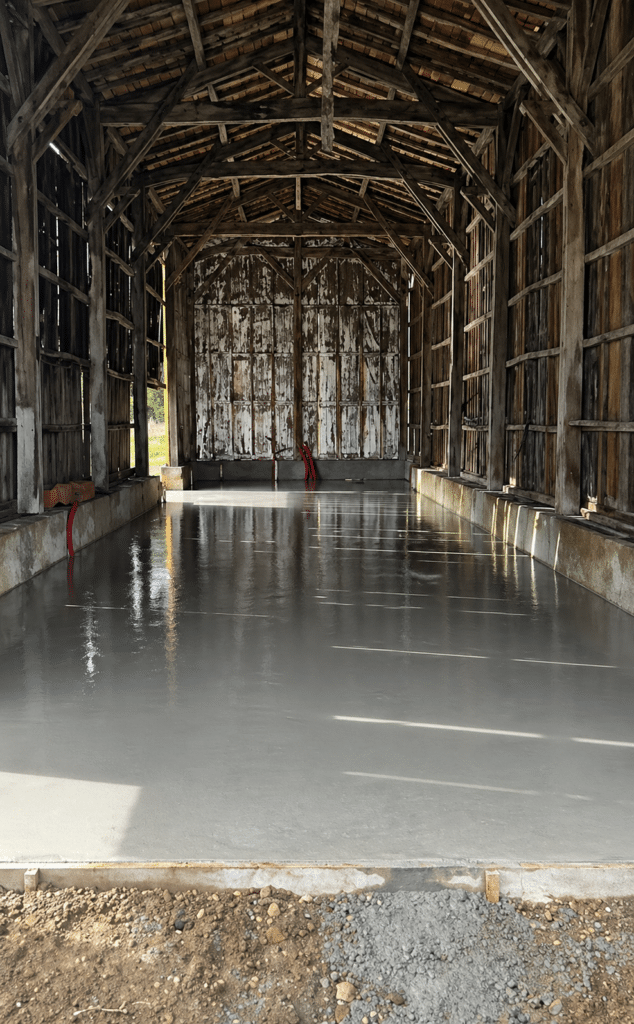 Dalle en béton lissé fraîchement coulée à l'intérieur d'une grange ancienne en bois en cours de rénovation.