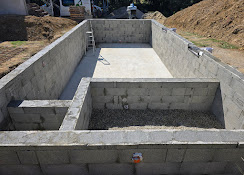 Construction d'une piscine en parpaings avec bassin principal et spa attenant sur un chantier de terrassement.