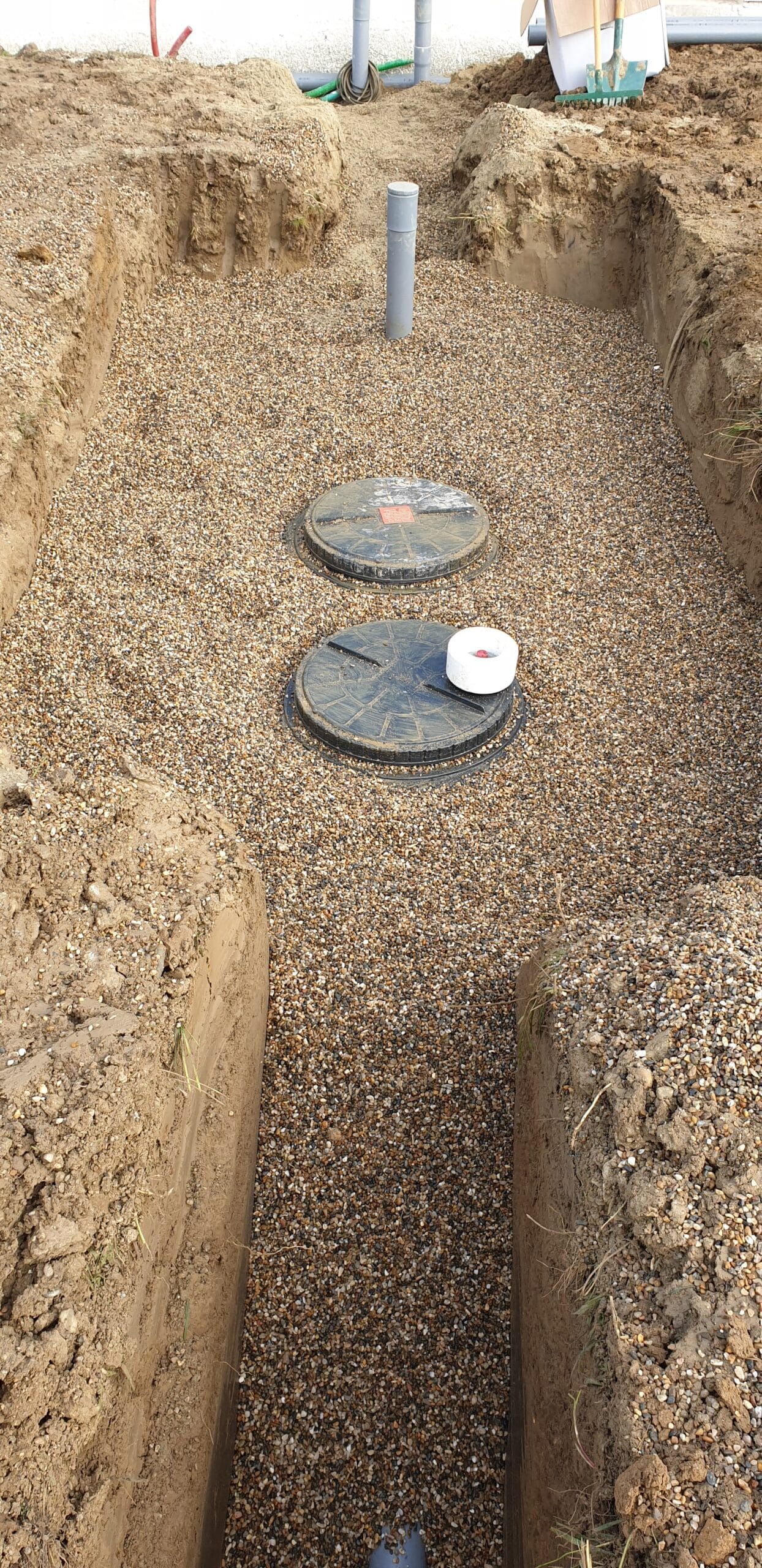 Installation d'une fosse septique dans une tranchée de gravier avec deux couvercles d'accès et un évent vertical.