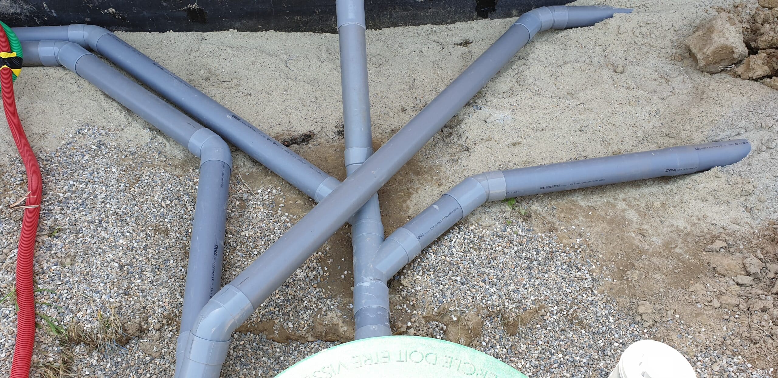Tuyaux PVC gris DYKA SOTRABAT pour évacuation des eaux usées sur lit de gravier et sable.
