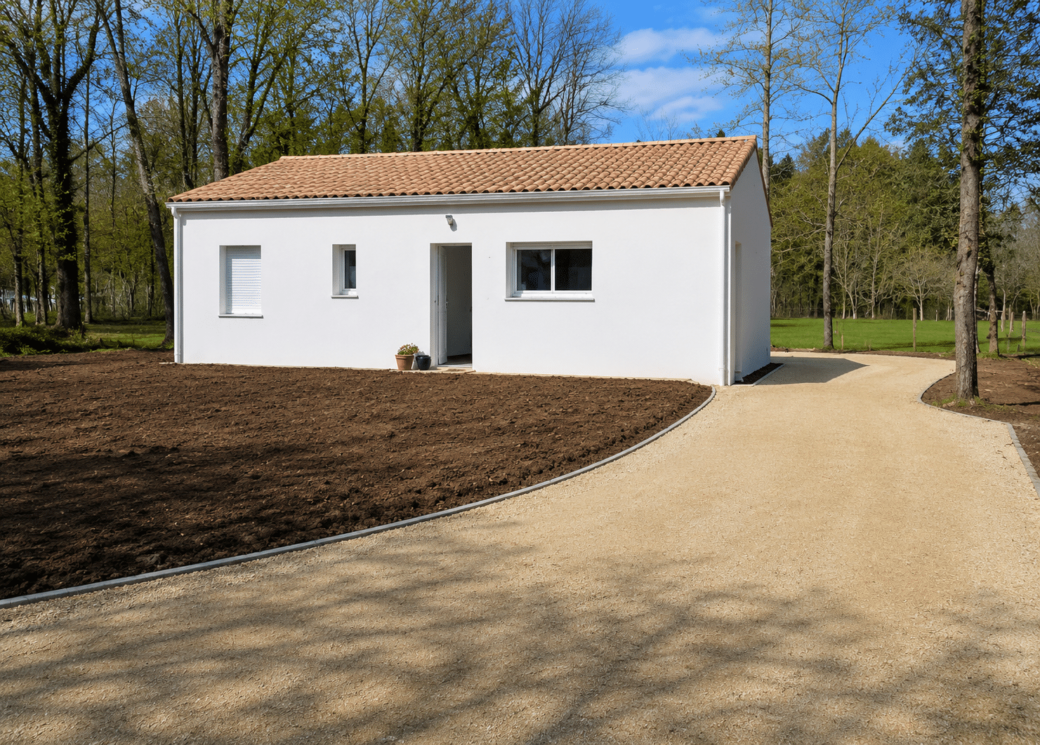 Maison blanche moderne avec toit en tuiles, allée en gravier et terrain aménagé bordé d'arbres.